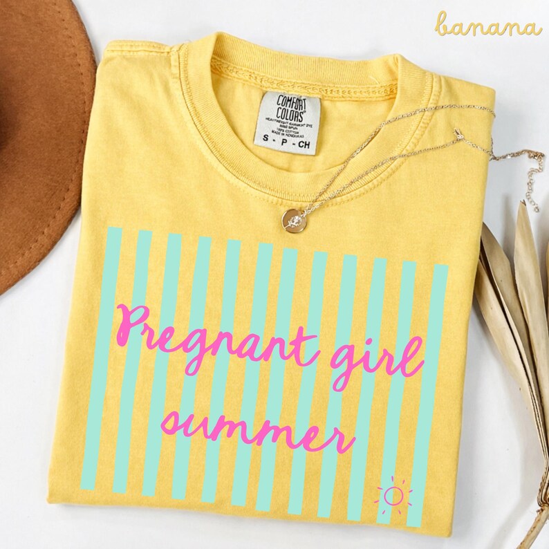 Banana yellow Comfort Colors shirt with vertical mint green stripes and pink script text reading “Pregnant girl summer” centered across the front, with a small pink sun icon detail at the bottom corner.
