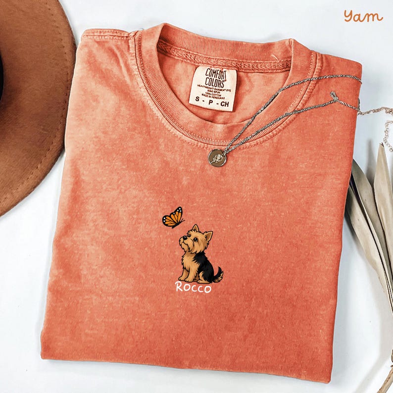 Folded yam  Comfort Colors shirt with cute Yorkshire Terrier puppy and butterfly graphic, personalized dog lover tee with custom pet name, minimalist pet shirt flat lay aesthetic gift idea.