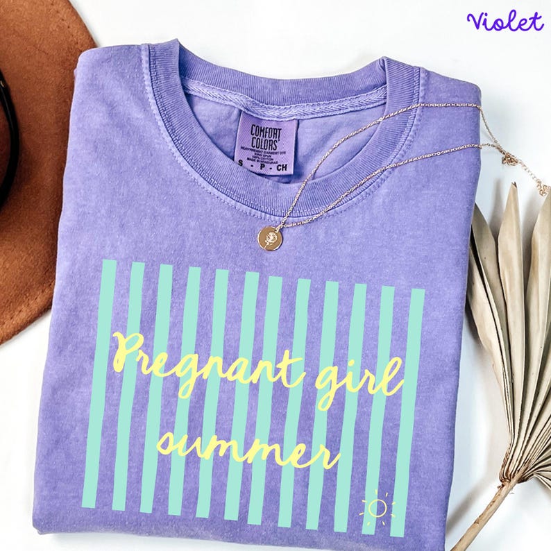 Violet Comfort Colors shirt with vertical mint green stripes and yellow script text reading “Pregnant girl summer” centered across the front, with a small yellow sun icon detail at the bottom corner.