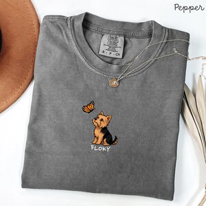 Folded PEPPER Comfort Colors shirt with cute Yorkshire Terrier puppy and butterfly graphic, personalized dog lover tee with custom pet name, minimalist pet shirt flat lay aesthetic gift idea.