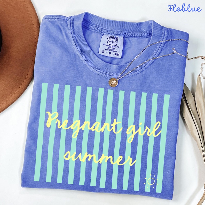 Flo blue Comfort Colors shirt with vertical mint green stripes and yellow script text reading “Pregnant girl summer” centered across the front, with a small yellow sun icon detail at the bottom corner.
