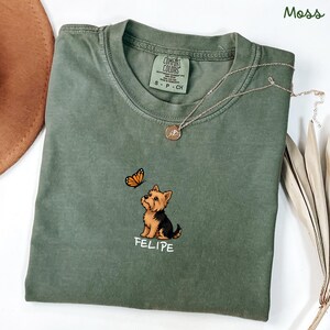 Folded MOSS Comfort Colors shirt with cute Yorkshire Terrier puppy and butterfly graphic, personalized dog lover tee with custom pet name, minimalist pet shirt flat lay aesthetic gift idea.
