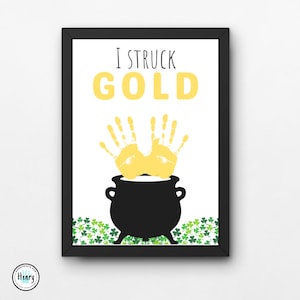 May include: A printable art print with a black frame. The print features a black pot with two yellow handprints on top. The text "I struck GOLD" is above the pot. Green shamrocks are at the bottom of the print.
