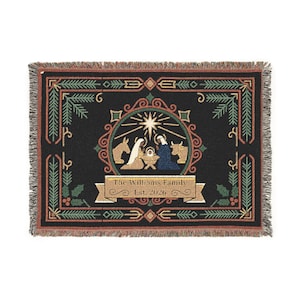 May include: A black woven throw blanket featuring a central nativity scene with a bright star, surrounded by a decorative border of pine branches and holly. A tan banner at the bottom displays the text The Williams Family Est. 2026.