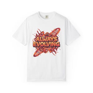 Puede incluir: Camiseta blanca con el texto "ALWAYS EVOLVING" en naranja y rojo, acompañada de un diseño estilizado de cadena de ADN. El gráfico incorpora un efecto de salpicadura. La camiseta es de cuello redondo.