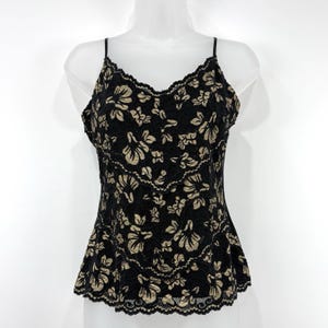 Op de afbeelding: Zwarte camisole top met een bloemen kanten design. De top heeft dunne spaghettibandjes en een geschulpte halslijn en zoom. Het bloemenpatroon is in een contrasterende bruine kleur, wat een delicate en vrouwelijke uitstraling creëert.