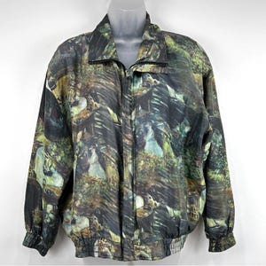 May include: A full-zip jacket with a unique, all-over print. The jacket features a black zipper, collar, and cuffs. The pattern is a mix of green, brown, and black, resembling a forest or landscape design. The jacket has a relaxed fit and elastic cuffs and hem.