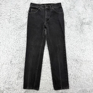 Puede incluir: Vaqueros de mezclilla negros con un diseño clásico de cinco bolsillos. Los vaqueros tienen un corte de pierna recta y cierre de botón y cremallera. El logotipo de Lee es visible en el bolsillo delantero. Los vaqueros se muestran sobre una superficie blanca y gris esponjosa.