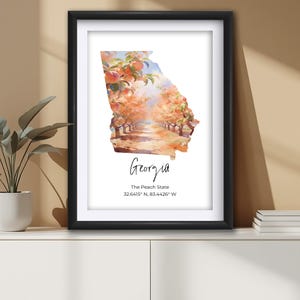 May include: Framed art print featuring a watercolor painting of Georgia's outline filled with a peach orchard scene. The print includes the word "Georgia" in cursive and the text "The Peach State".