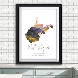 May include: Framed watercolor print of West Virginia in a black frame. The state outline is filled with a colorful landscape and a bridge. The text "West Virginia" and "The Mountain State" are below the image.