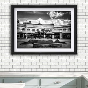 May include: Black and white framed print of the Churchill Downs racetrack. The image features a statue of a horse and jockey, with the word "Barbaro" on the base. The racetrack's architecture and cloudy sky are visible in the background.