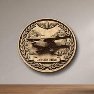 May include: A circular wooden wall plaque featuring a carved light aircraft in the centre, surrounded by clouds and a laurel wreath border. At the top is a winged emblem, and a banner at the bottom displays the text Captain Mike.