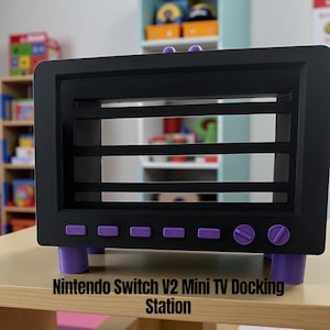 May include: A black Nintendo Switch V2 Mini TV Docking Station with purple accents. The docking station has a rectangular shape with horizontal slats and purple buttons and feet. The text "Nintendo Switch V2 Mini TV Docking Station" is at the bottom.