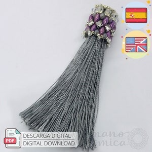 Puede incluir: Una borla gris con una parte superior de cuentas con cuentas moradas, transparentes y plateadas. La borla está hecha de muchos hilos grises. La imagen también incluye el texto "DESCARGA DIGITAL DIGITAL DOWNLOAD".