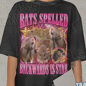 May include: Black t-shirt with a graphic design featuring several brown rats and the text "RATS SPELLED BACKWARDS IS STAR" in pink. The design includes stars and a pink lightning bolt background.
