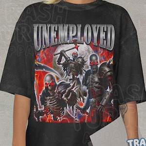 May include: Black t-shirt with the word "UNEMPLOYED" in silver lettering. The graphic features skeletal figures with red eyes and weapons against a red and white background. The brand "Trash Turtle Apparel" is visible.