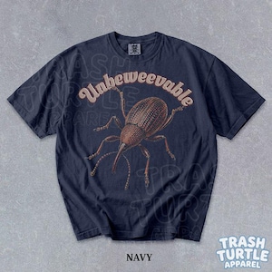 Puede incluir: Una camiseta azul marino de manga corta con una ilustraci&oacute;n marr&oacute;n de un insecto gorgojo centrada en el pecho. Sobre el insecto, el texto dice Unbeweevable en una fuente clara y curva. La camiseta tiene un cuello redondo y una etiqueta.