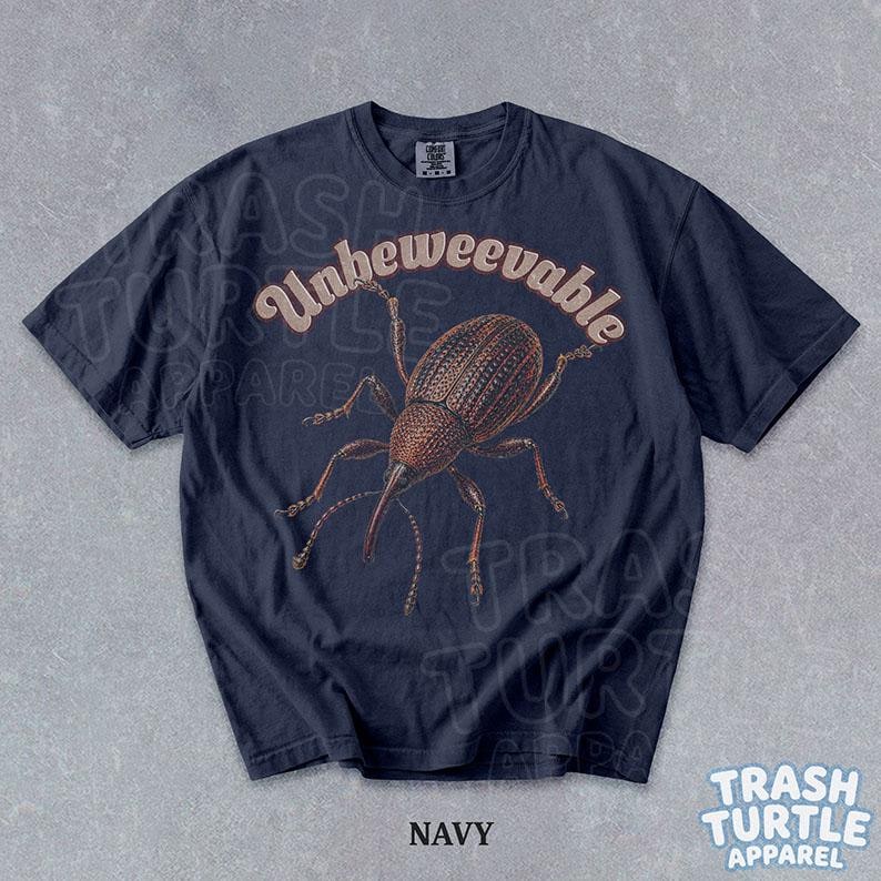 Puede incluir: Una camiseta azul marino de manga corta con una ilustraci&oacute;n marr&oacute;n de un insecto gorgojo centrada en el pecho. Sobre el insecto, el texto dice Unbeweevable en una fuente clara y curva. La camiseta tiene un cuello redondo y una etiqueta.