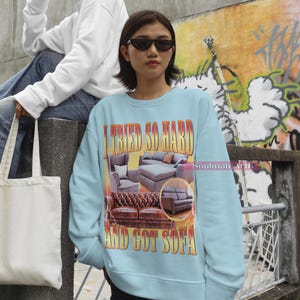 May include: A light blue sweatshirt with a graphic print of a couch and the text "I tried so hard and got sofa".
