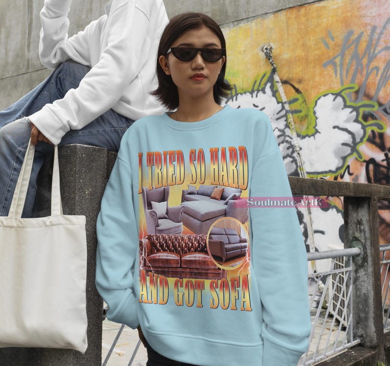 May include: A light blue sweatshirt with a graphic print of a couch and the text "I tried so hard and got sofa".