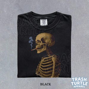 Puede incluir: Camiseta negra con una ilustraci&oacute;n detallada de un esqueleto fumando un cigarrillo. El esqueleto est&aacute; representado de perfil, con un cr&aacute;neo y una caja tor&aacute;cica. La camiseta tiene el texto "BLACK" en la parte inferior y la marca "TRASH TURTLE APPAREL".