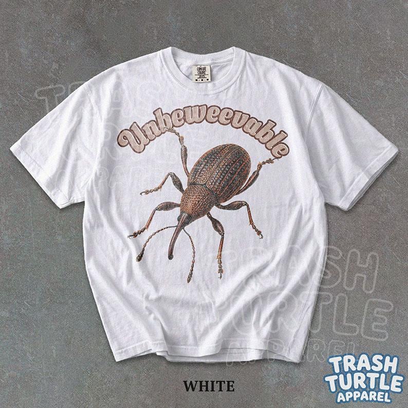 Puede incluir: Una camiseta blanca de manga corta con un gr&aacute;fico de un insecto gorgojo marr&oacute;n en el centro. Sobre el insecto, la palabra Unbeweevable est&aacute; impresa en una fuente curva de color marr&oacute;n claro. La camiseta tiene cuello redondo y corte est&aacute;ndar.