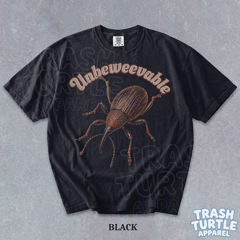 Puede incluir: Una camiseta negra de manga corta con una ilustraci&oacute;n marr&oacute;n detallada de un gorgojo en el centro. Sobre el insecto, la palabra Unbeweevable est&aacute; impresa en una fuente curva de color claro. La camiseta tiene cuello redondo y una etiqueta.