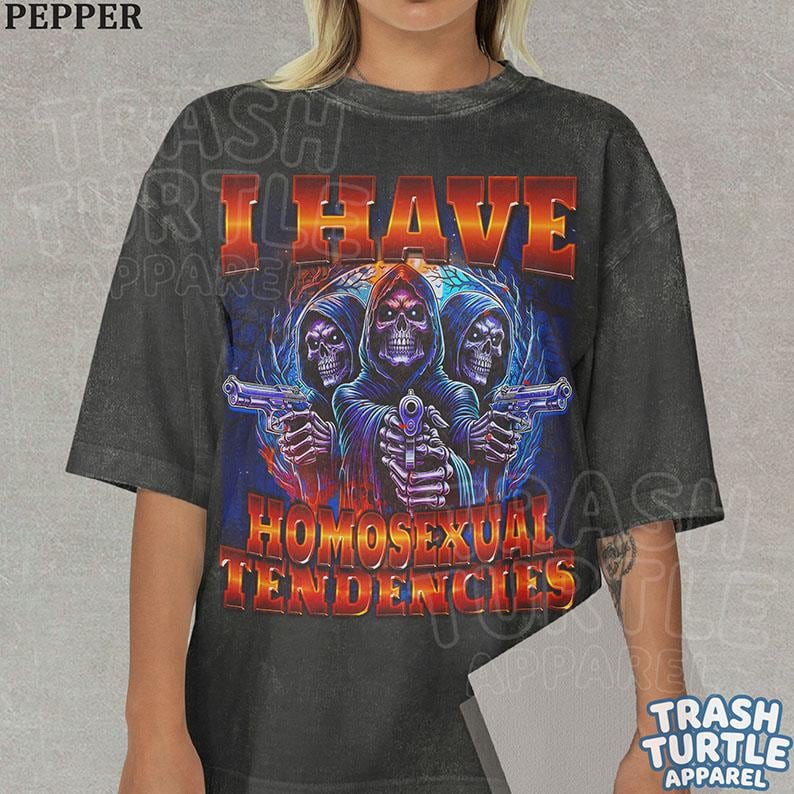 Peut inclure: Un t-shirt gris anthracite &agrave; manches courtes avec une impression graphique de trois squelettes encapuchonn&eacute;s tenant des pistolets. Le texte I HAVE HOMOSEXUAL TENDENCIES est imprim&eacute; dans une police d&eacute;grad&eacute;e orange et jaune vif.