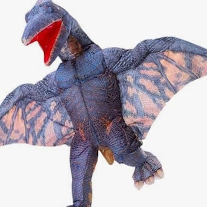 May include: A full-body inflatable pterodactyl costume featuring a textured blue and purple scaly pattern, large outstretched wings with light pink undersides, and a head piece with an open mouth revealing a bright red interior lining.