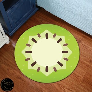 May include: A green and brown round rug with a kiwi fruit design. The rug has a light green background with a dark green kiwi fruit design in the center. The kiwi fruit design has a brown seed pattern.