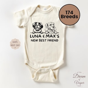 May include: Cream-colored baby onesie featuring a black and white illustration of two dogs above the text "LUNA & MAX'S NEW BEST FRIEND". A brown circle displays "174 Breeds". The design includes the text "Dream of Vesper Design".