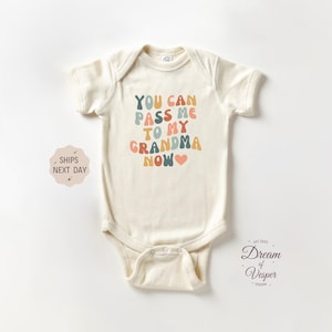 Peut inclure: Body bébé crème avec l'inscription "YOU CAN PASS ME TO MY GRANDMA NOW" en lettres colorées de style rétro. Un petit cœur rose est inclus. Le body a des manches courtes et une fermeture à boutons-pression.