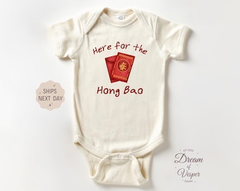 May include: Cream-colored baby bodysuit with the text "Here for the Hong Bao" in red. The design includes a red envelope and a red card with Chinese characters. A cute and festive outfit for a baby.