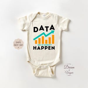 May include: A cream colored baby onesie with a black graphic that says "DATA OR IT DIDN'T HAPPEN" with a green and orange graph icon.