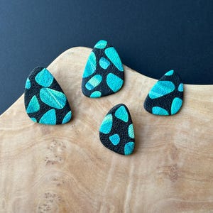 May include: Four black and turquoise blue teardrop-shaped earrings with a speckled pattern.