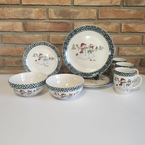 May include: A set of snowman themed dinnerware, including two bowls, two plates, a large platter, and four mugs. The dishes feature a green and white speckled pattern with a snowman design.