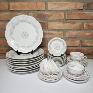 May include: A set of white porcelain dinnerware with a delicate pink floral pattern and gold trim. The set includes plates, bowls, and cups and saucers.