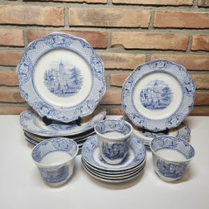 May include: A collection of blue and white porcelain tableware, including plates, saucers, and cups. The plates feature a detailed landscape scene in the center, with a decorative border. The cups and saucers have matching designs.