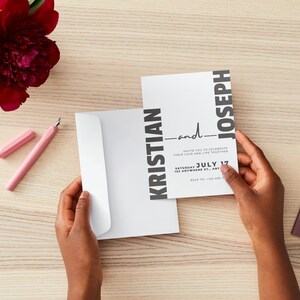 May include: A white wedding invitation with black text. The invitation reads "Kristian and Joseph invite you to celebrate their love and life together Saturday, July 17, 123 Anywhere St., Anytown, RSVP to: 123-456-7890."