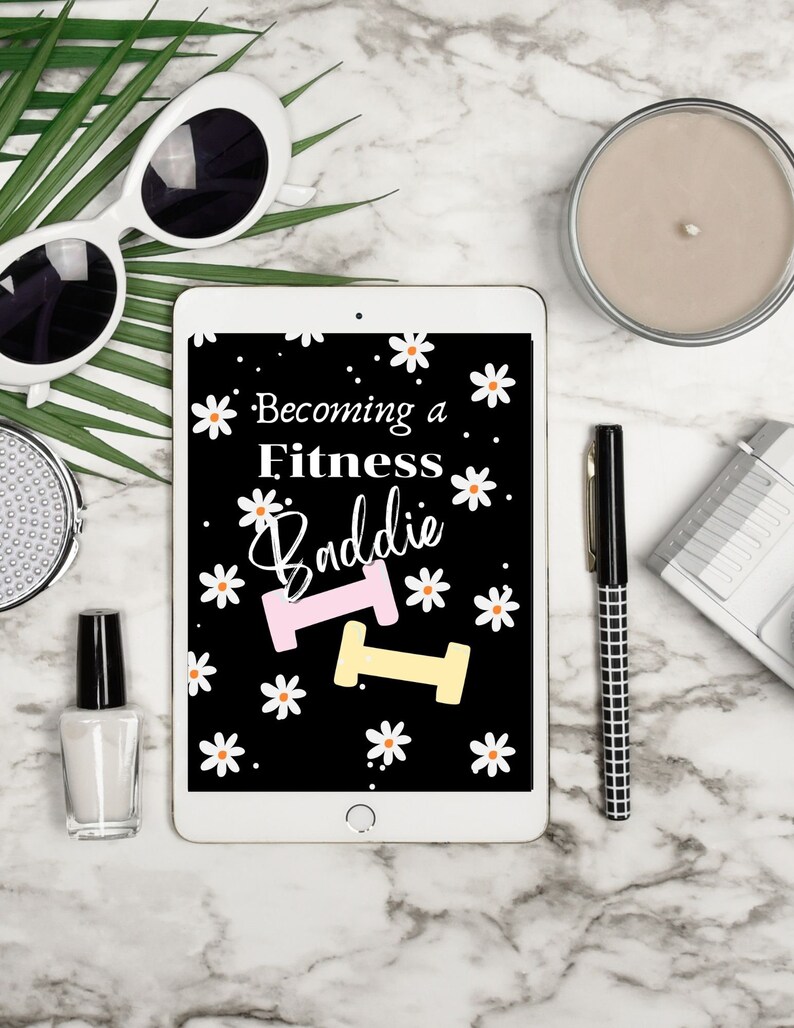 Puede incluir: Una tableta blanca con una pantalla negra que muestra el texto "Becoming a Fitness Baddie" con un gr&aacute;fico de mancuerna rosa y amarilla y margaritas blancas sobre un fondo negro.