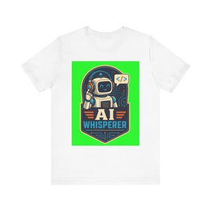 Peut inclure: Un t-shirt blanc avec un motif central représentant un robot souriant portant un casque audio. Le robot est placé dans un écusson bleu foncé sur fond vert vif. Le texte AI WHISPERER et une bulle avec des balises de code sont présents.