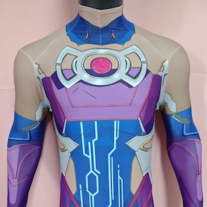 Może przedstawiać: Futurystyczny kostium na całe ciało w kolorze niebieskim, fioletowym i srebrnym. Garnitur ma skomplikowane geometryczne wzory i okrągły emblemat na klatce piersiowej. Posiada długie rękawy, rękawice i wysoki kołnierz.