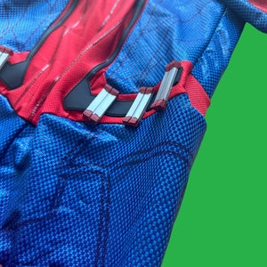 May include: A red and blue spandex costume with a spider logo on the chest. The costume has a black web pattern and silver and red accents on the waist.