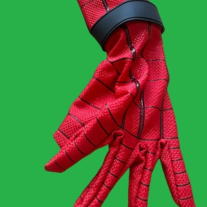 May include: Red and black Spiderman glove with a black wrist strap. The glove has a webbed design.