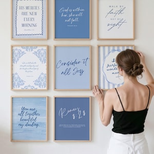 May include: A collection of eight framed wall art prints featuring blue and white color schemes with various inspirational quotes and scripture verses in different typography styles, arranged in a grid pattern on a plain wall surface.