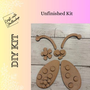May include: Unfinished DIY kit with wooden pieces to create a butterfly. The kit includes two oval-shaped body pieces, two curved antennae, two eye pieces, and two flower-shaped pieces. The text "DIY KIT" and "Unfinished Kit" are visible.