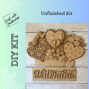 May include: Unfinished DIY kit featuring wooden Valentine's Day decorations. The kit includes heart-shaped cutouts with floral and bow accents, and a sign that says "Valentine". The kit is designed to be painted or decorated.