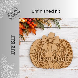 May include: An unfinished wooden pumpkin cutout featuring a layered bow at the top and the word Thankful in script lettering. The surface is decorated with various engraved patterns including dots, leaves, hearts, flowers, and plaid designs.