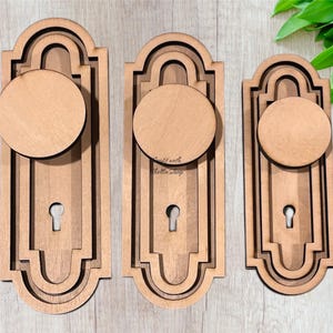 May include: Three unfinished wooden door knob blanks with a decorative arched design. The blanks are different sizes and are ready to be painted or stained.