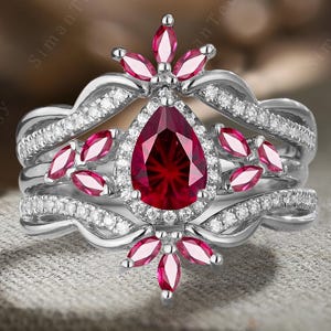 Delikat päronfärgat fyrverkerislipat rubin förlovningsring i 10K/14K vitguld med juli-födelsesten och förstärkt dubbelböjd vigselring